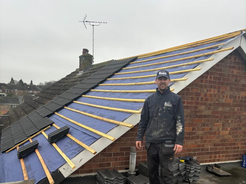A roofer laying new tiles over the battens